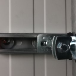 HR-MONT Service - Szyna montażowa z żółtą zaślepką, przymocowana do ściany, obejma na rurze wentylacyjnej, widoczne śruby i nakrętki mocujące.