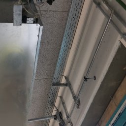 HR-MONT Service - Widok instalacji pod stropem z widocznymi rurami, korytkami kablowymi i elementami mocującymi.