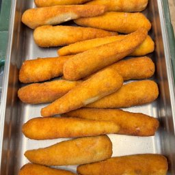 KONFIGURATOR IMPREZY Catering & Bankiet & Event www.konfiguratorimprezy.pl - Smażone krokiety w srebrnej, metalowej tacy cateringowej, ułożone warstwami. Złocista panierka, widoczne nierówności i detale tekstury. Przygotowane do serwowania.