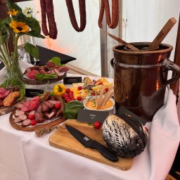 KONFIGURATOR IMPREZY Catering & Bankiet & Event www.konfiguratorimprezy.pl - Stół z przekąskami: wędliny, sery, chleb i smalec. Dekoracja z kwiatów słonecznika. Wiejski stół z drewnianymi elementami. Aranżacja cateringu na przyjęcie.