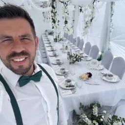 Uroczysty stół komunijny w białym namiocie, dekoracje kwiatowe i elegancka zastawa. Szamotuły.