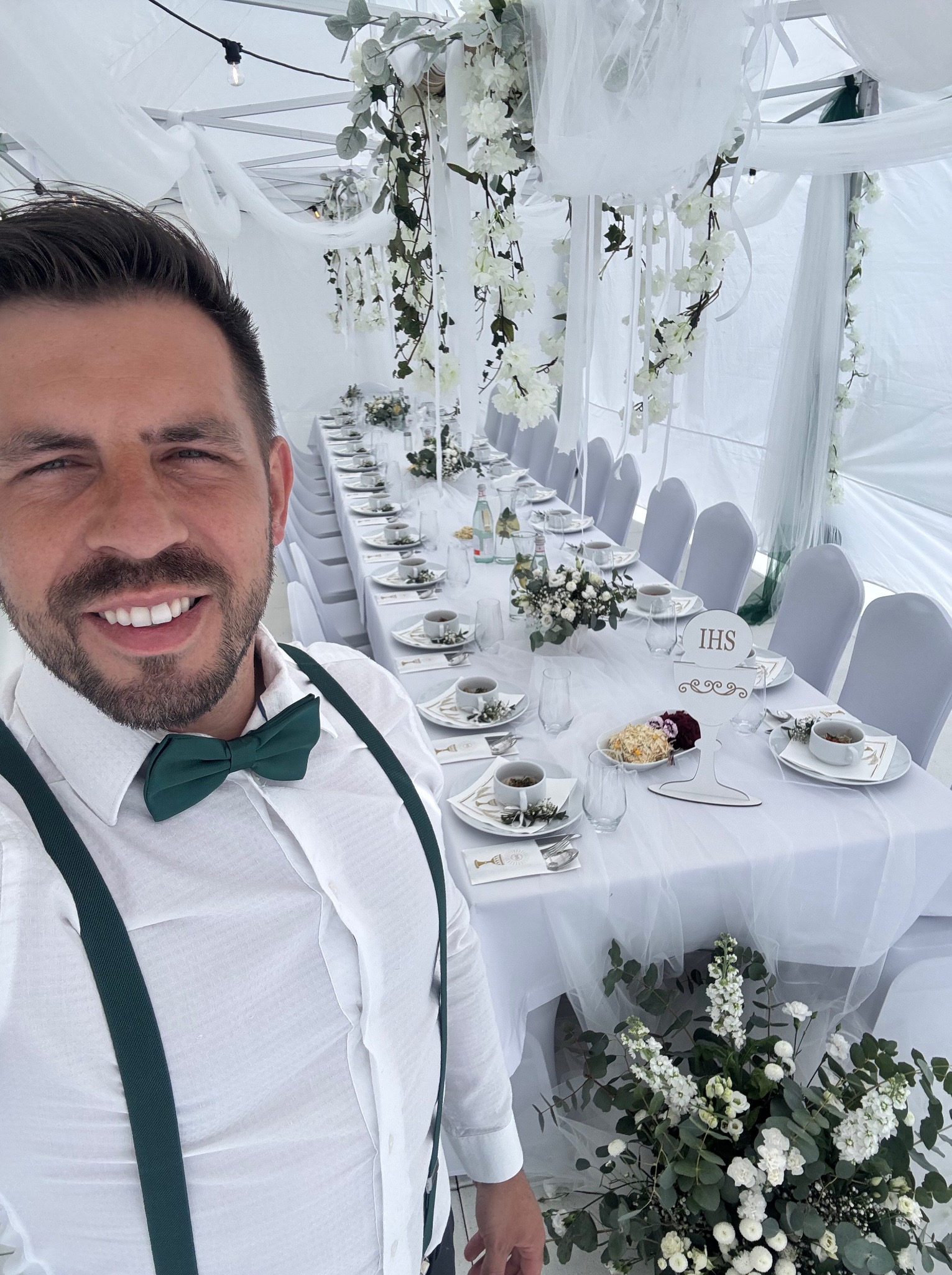 Uroczysty stół komunijny w białym namiocie, dekoracje kwiatowe i elegancka zastawa. Szamotuły.