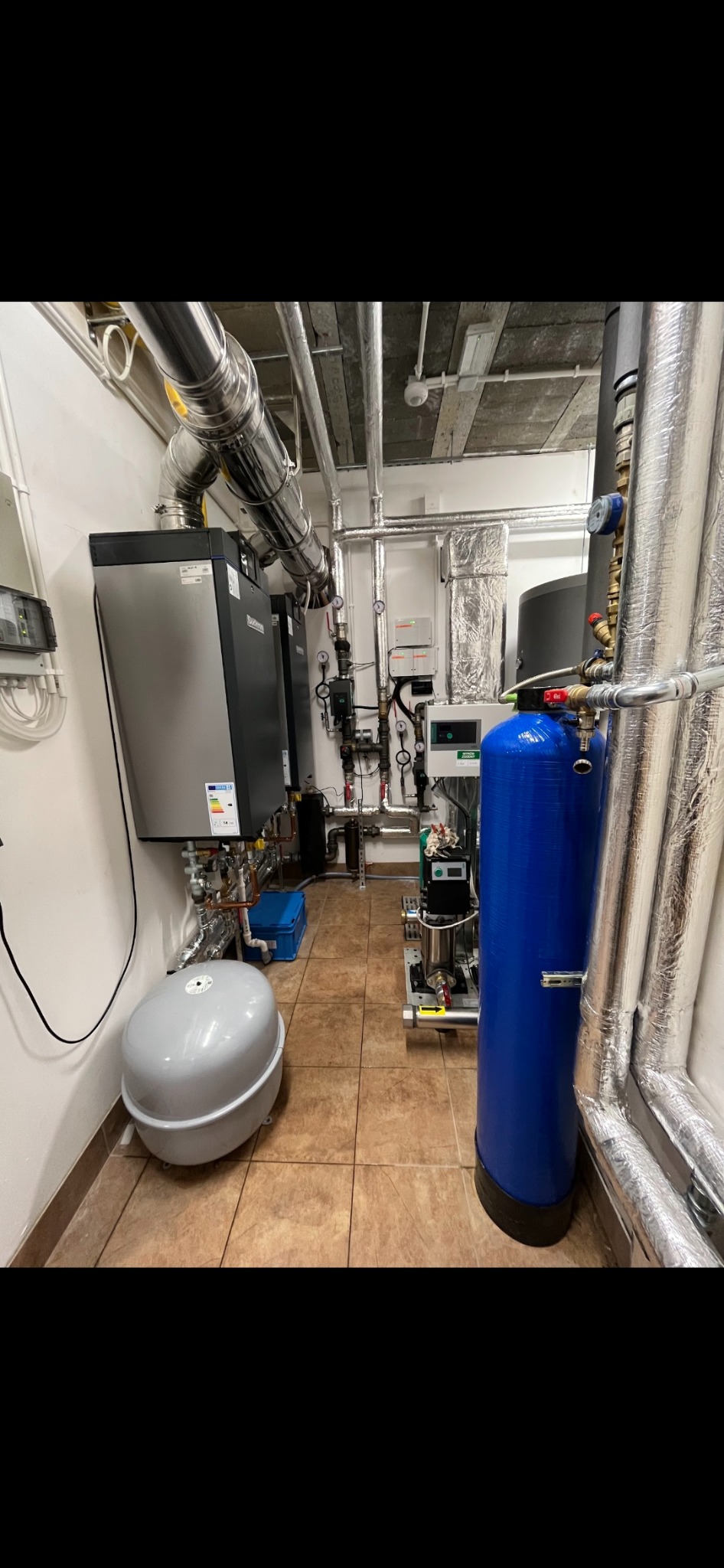 Kompletna instalacja z pompą ciepła i zbiornikiem buforowym w kotłowni w Namysłowie, widoczne liczne rury i zawory.