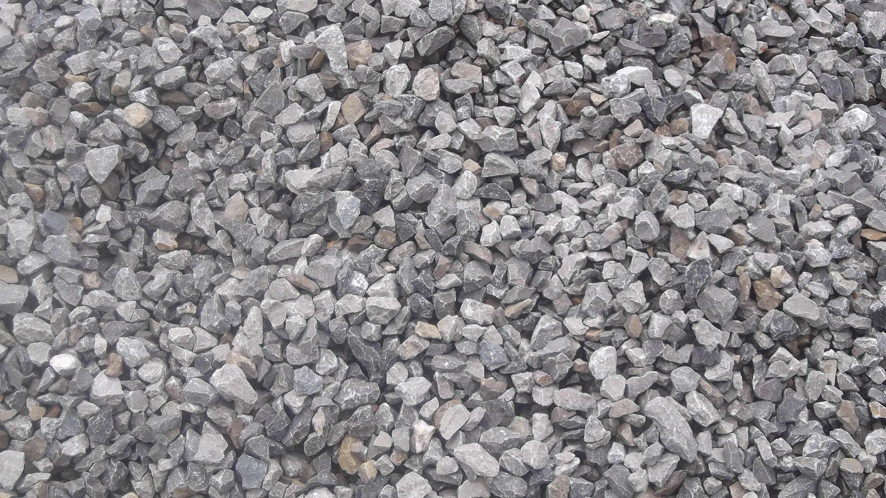 Szare kamienie o ostrych krawędziach i zróżnicowanej wielkości, tworzące równą warstwę.