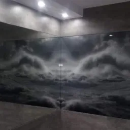 Nowoczesna łazienka z szarą, betonową okładziną i dużym, szklanym panelem z motywem burzliwego morza i latarni morskiej, odbijającym się w lustrze.