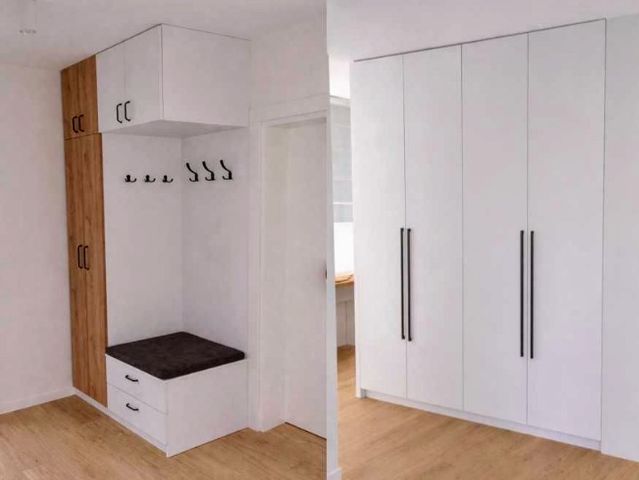 Biała szafa wnękowa z siedziskiem i wieszakami, z drewnianym akcentem, obok szafa z długimi uchwytami. Realizacja z Polanowa, idealna do przedpokoju.
