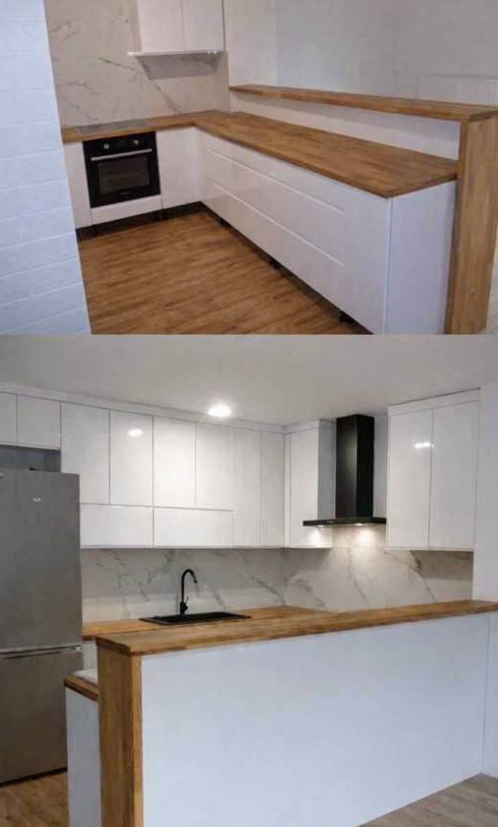 Nowoczesna kuchnia z białymi szafkami i drewnianym blatem, podzielona na dwie części: dolną z piekarnikiem i górną z okapem, marmurowa ściana.