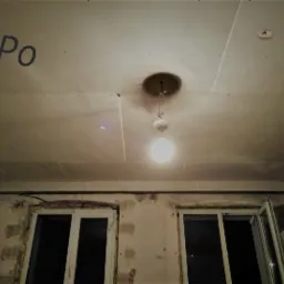 Sufit z płyt gipsowo-kartonowych przed szpachlowaniem, widoczne okna i wisząca lampa