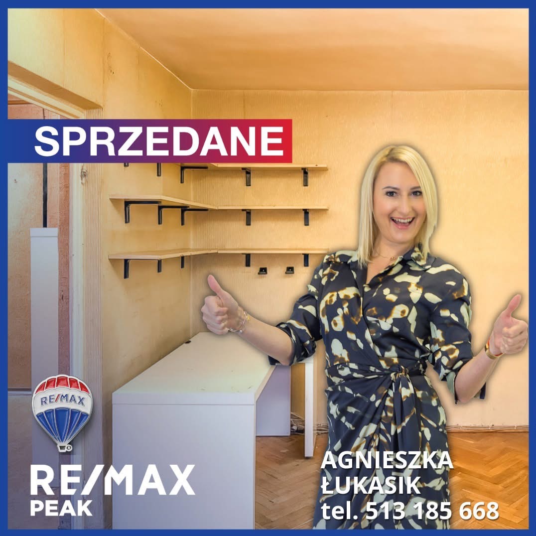 Uśmiechnięta blondynka z podniesionymi kciukami na tle sprzedanego pokoju z półkami. Logo RE/MAX Peak i dane kontaktowe agenta nieruchomości.