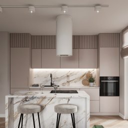 InterSpace Design - Nowoczesna kuchnia z wyspą wykończoną marmurem, jasnymi szafkami i okrągłym okapem, oświetlona reflektorami punktowymi.