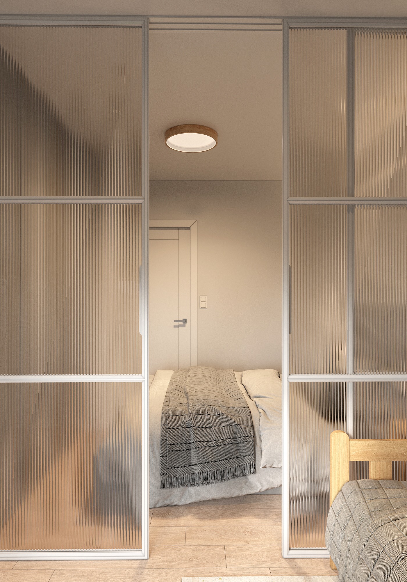 Sypialnia za szklanymi przesuwnymi drzwiami z ryflowanego szkła, widoczna część łóżka z szarą narzutą i drewniana rama łóżka, oświetlenie sufitowe w ciepłym odcieniu.