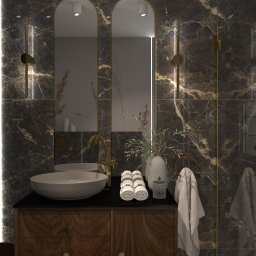 Dominika Chabiniak IDEAA - Elegancka łazienka z marmurowymi ścianami, owalną umywalką nablatową, złotą armaturą, dwoma lustrami w złotych ramach i oświetleniem LED po bokach.