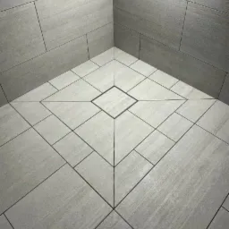 Wykończona łazienka z szarymi płytkami imitującymi drewno ułożonymi w geometryczny wzór na podłodze i ścianach, z centralnym kwadratem na podłodze.