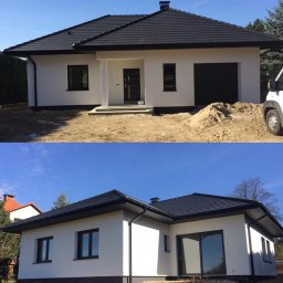 ELEBUD ELEWACJE DOCIEPLENIA - Nowoczesny dom jednorodzinny z białą elewacją i ciemną dachówką, widoczne okna z czarnymi ramami, brama garażowa oraz sterta piasku przed budynkiem.