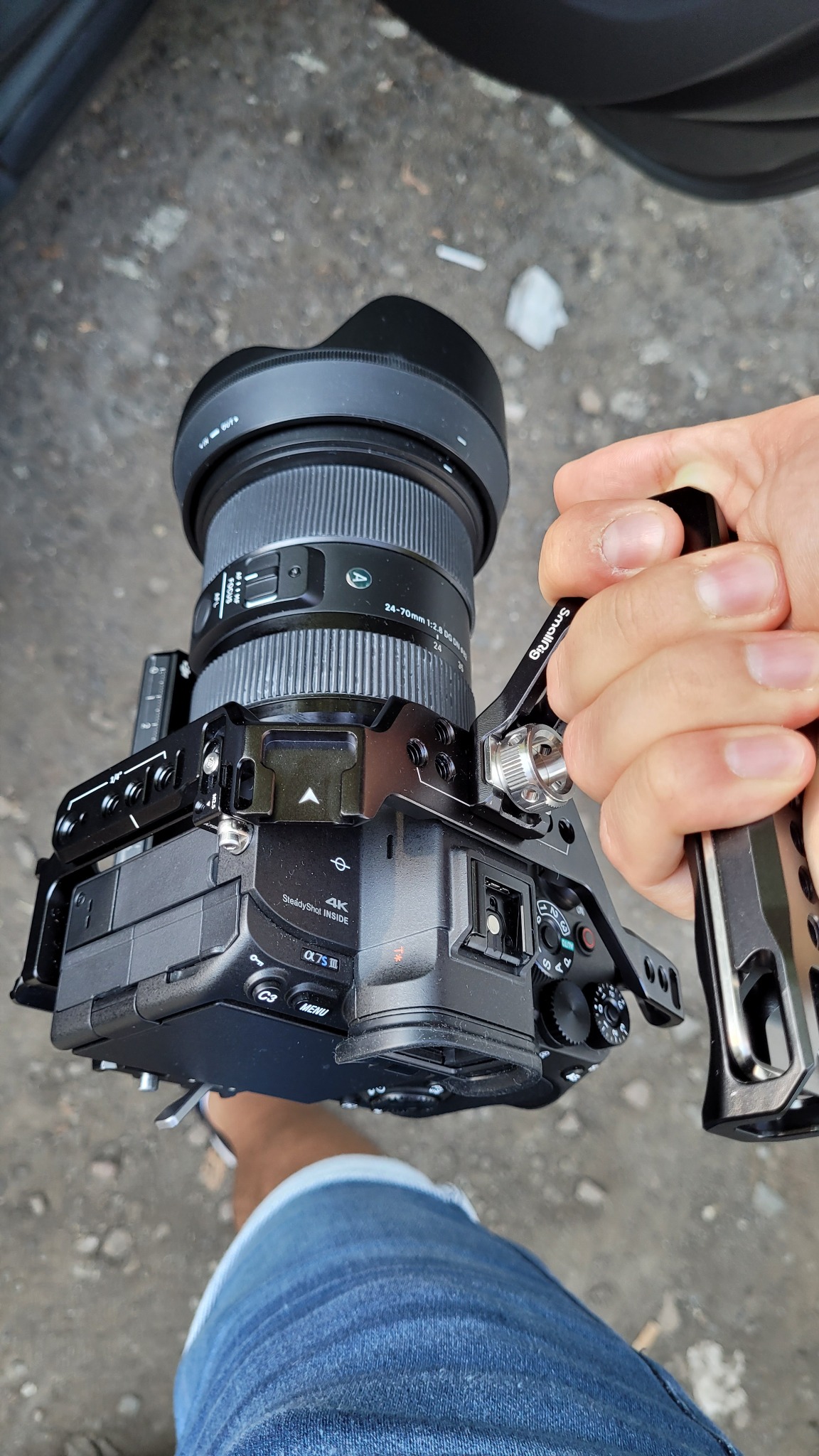 Profesjonalna kamera Sony Alpha 7S III z obiektywem 24-70mm i uchwytem SmallRig, trzymana w dłoni, widoczne ustawienia i oznaczenia 4K.