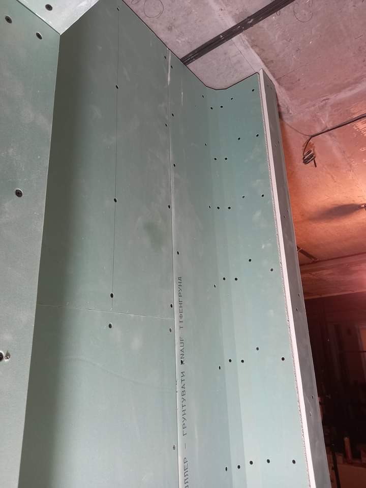 Narożnik wewnętrzny z płyt kartonowo-gipsowych, widoczne otwory po wkrętach, surowy stan przed dalszą obróbką, widoczny napis 'KNAUF TIEFENGRUND'.