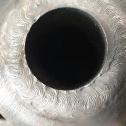 Detale spoiny okrężnej na metalowej rurze, widoczne ślady po spawaniu TIG.