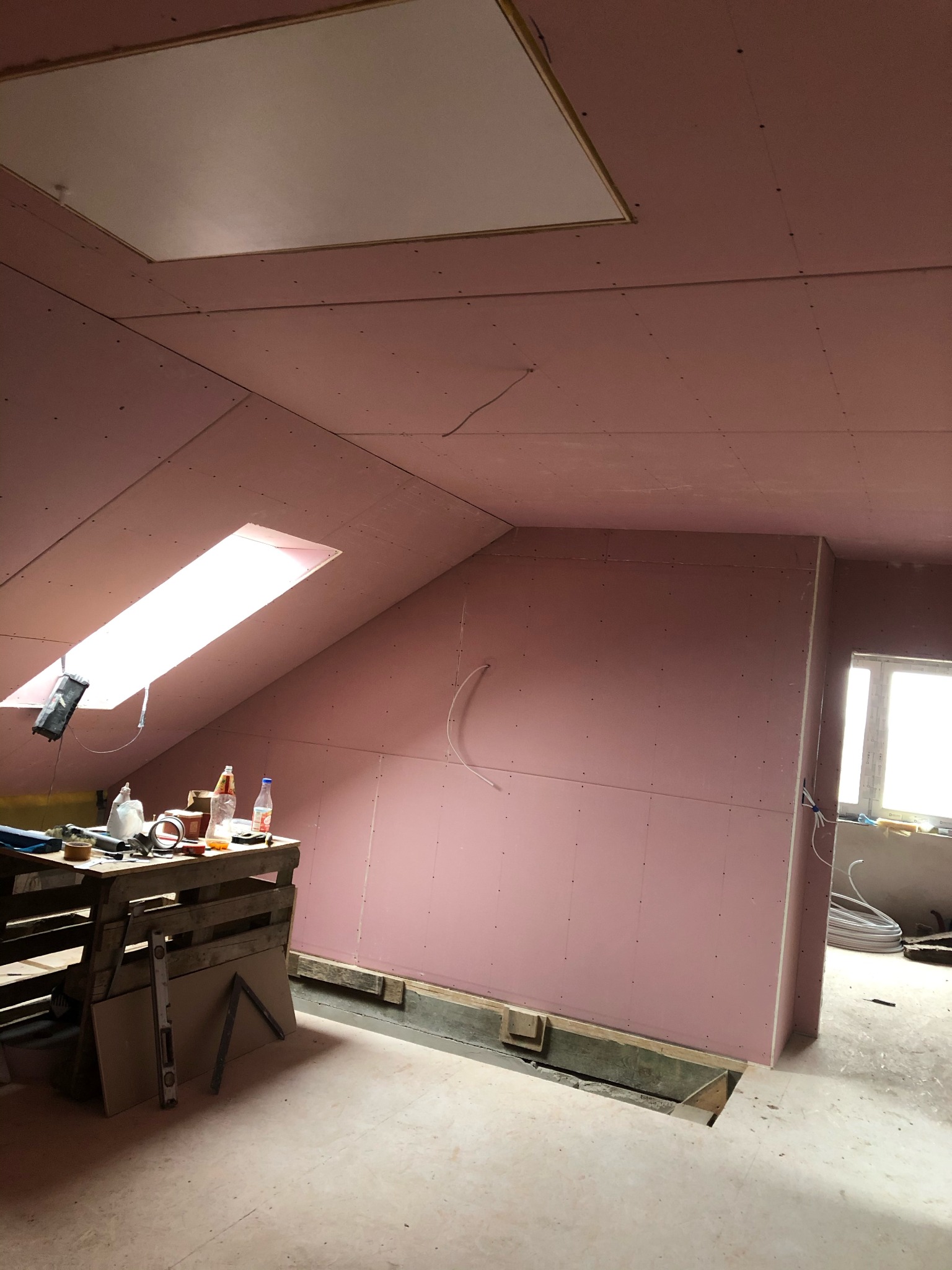 Montaż różowych płyt kartonowo-gipsowych na poddaszu w Hajnówce, widoczne narzędzia i materiały przygotowane do dalszych prac.