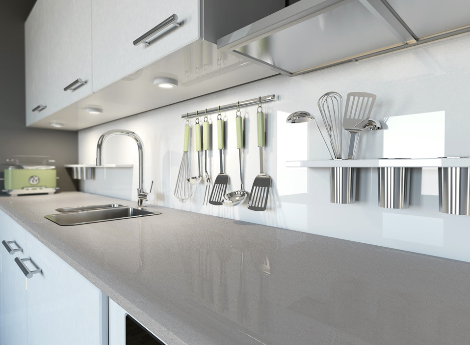 Błyszczący, szary blat kuchenny z widocznym zlewem i baterią, wiszące akcesoria kuchenne na relingu oraz białe szafki z metalowymi uchwytami, oświetlenie punktowe pod szafkami.