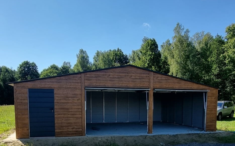 Dwustanowiskowy garaż z drewnopodobną elewacją, z bocznymi drzwiami i dwoma bramami segmentowymi otwartymi do połowy, na tle zieleni i błękitnego nieba.