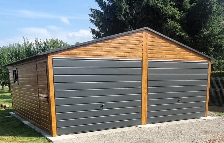 Dwustanowiskowy garaż z drewnianą elewacją i szarymi bramami segmentowymi, widoczny z boku, z oknem po lewej stronie