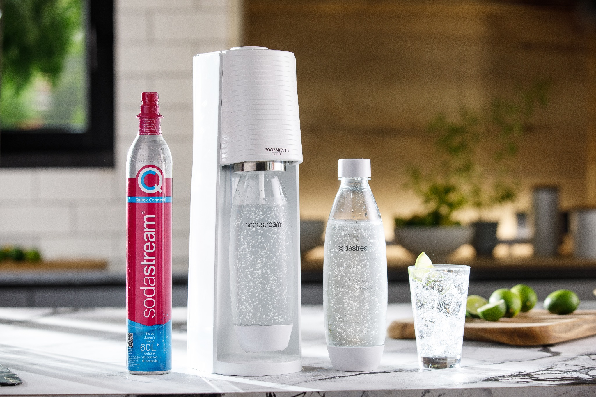 SodaStream Terra z butelką, nabojem CO2 i szklanką wody gazowanej z limonką na marmurowym blacie