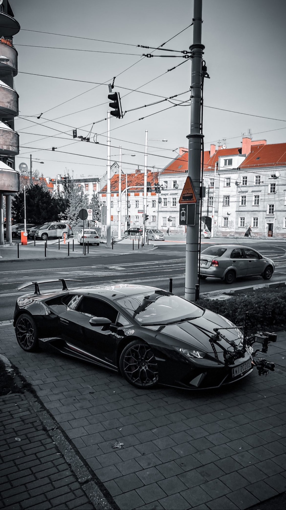 Czarny Lamborghini Huracan z zamontowanym sprzętem filmowym na ulicy miasta, przygotowany do ujęcia filmowego.