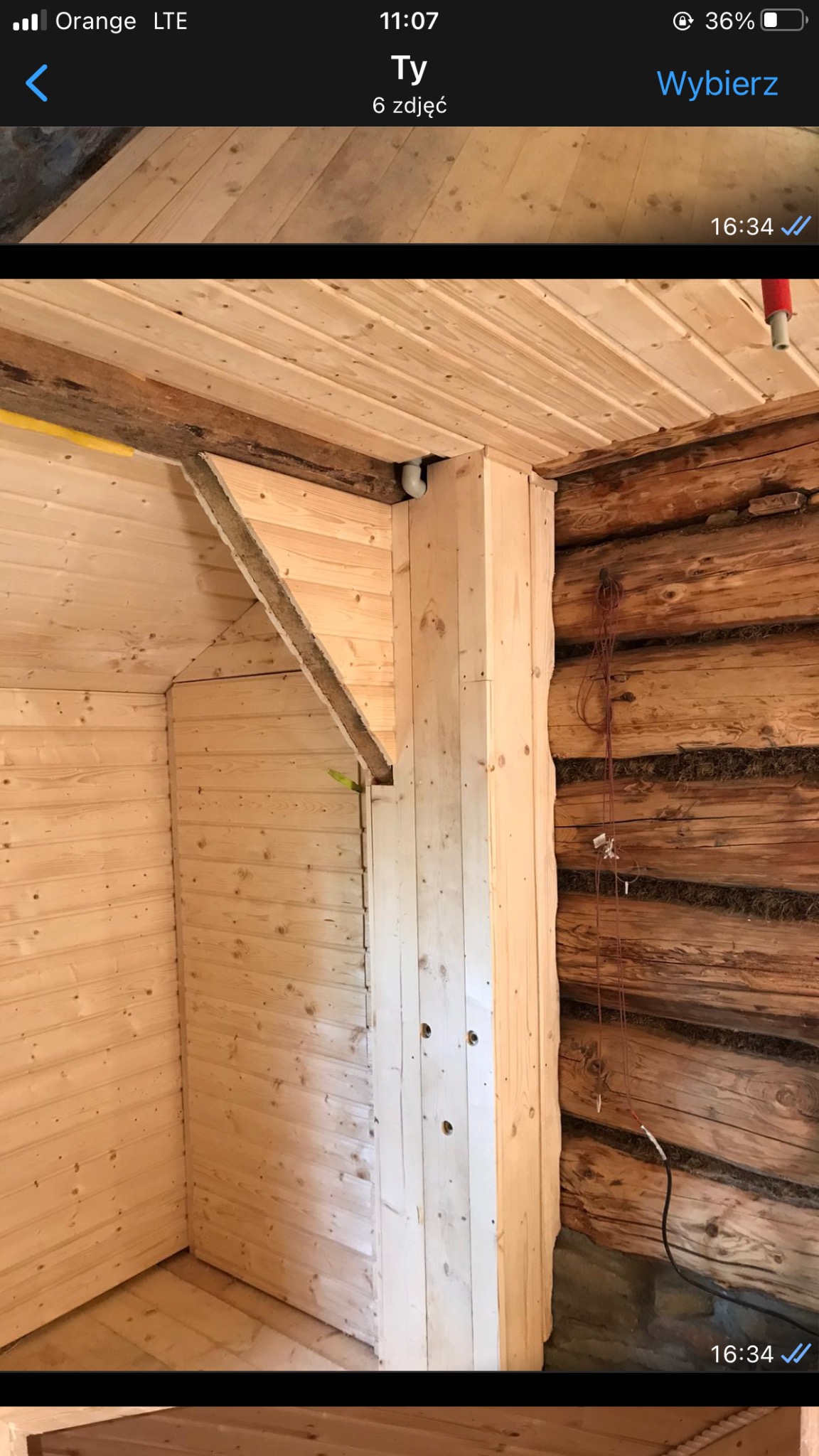 Wnętrze pomieszczenia w trakcie wykańczania drewnianą boazerią, widoczne połączenie nowego obicia z surową ścianą z bali, wystające przewody elektryczne.