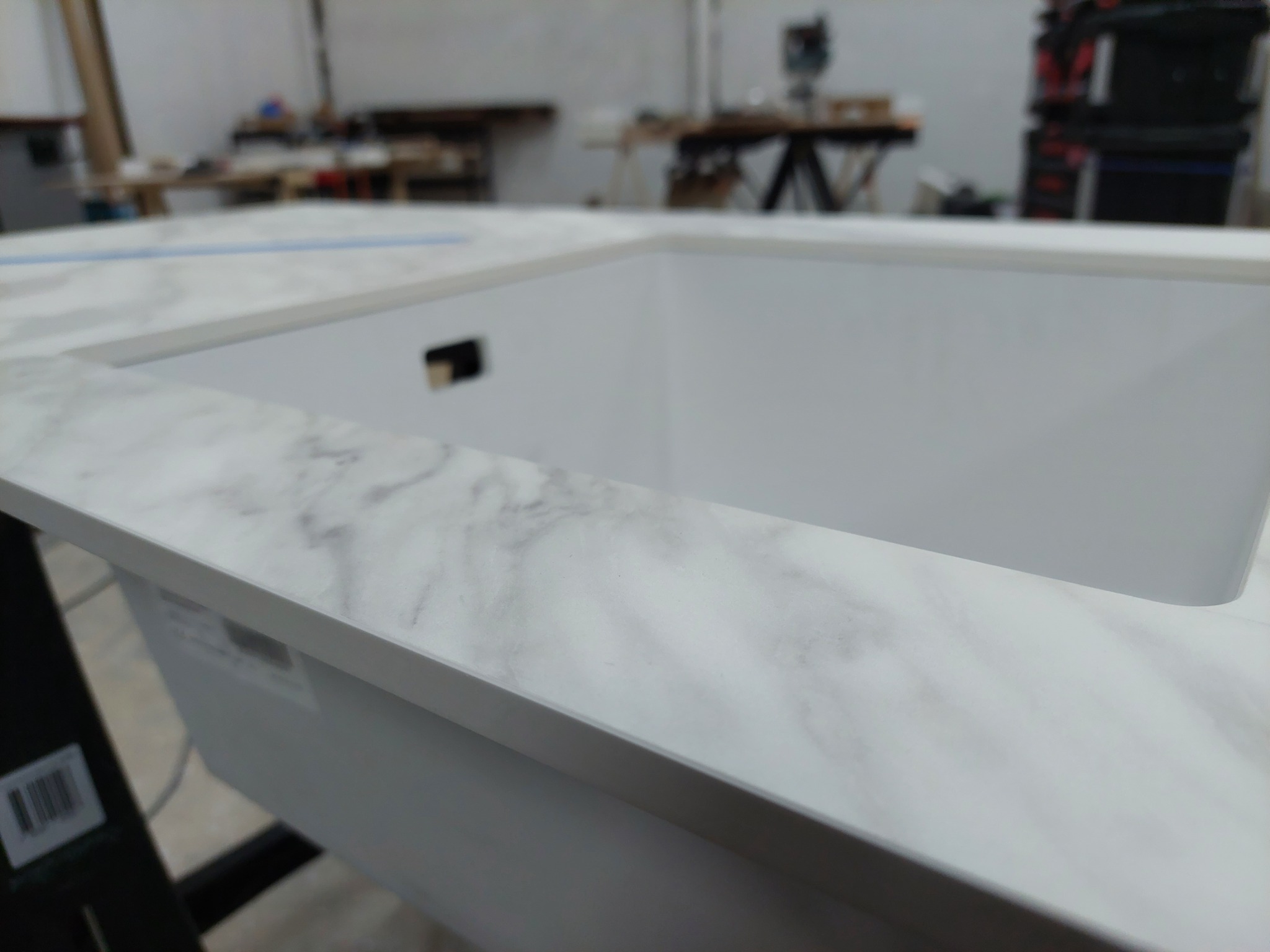 Blat kuchenny z białego marmuru z wyciętym otworem na zlew, widok z bliska w warsztacie stolarskim.