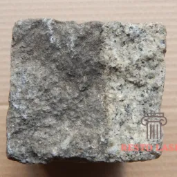 Kostka brukowa z granitu, z lewej strony zabrudzona, z prawej czysta, prezentująca efekt czyszczenia.