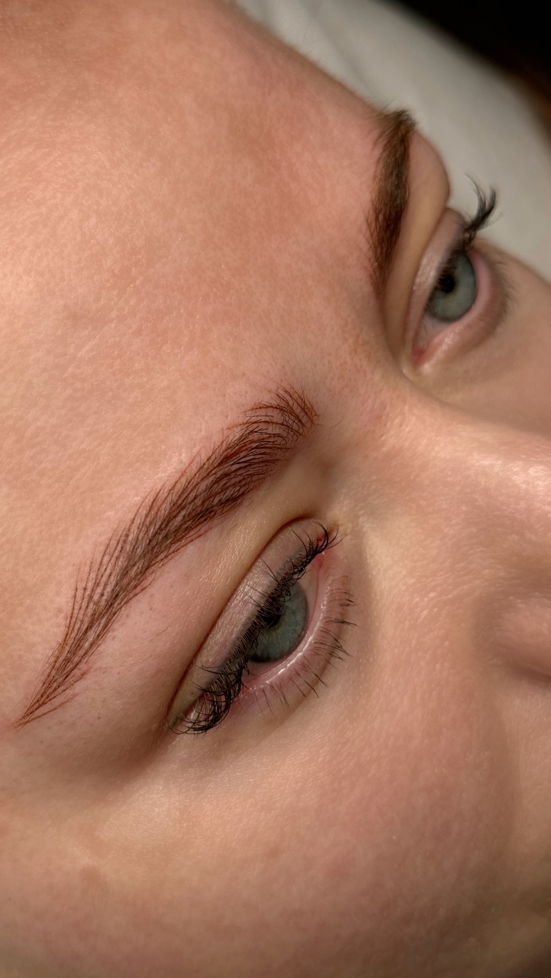 Zbliżenie na oko i brew po zabiegu microbladingu, widoczne precyzyjne linie imitujące włoski brwi.