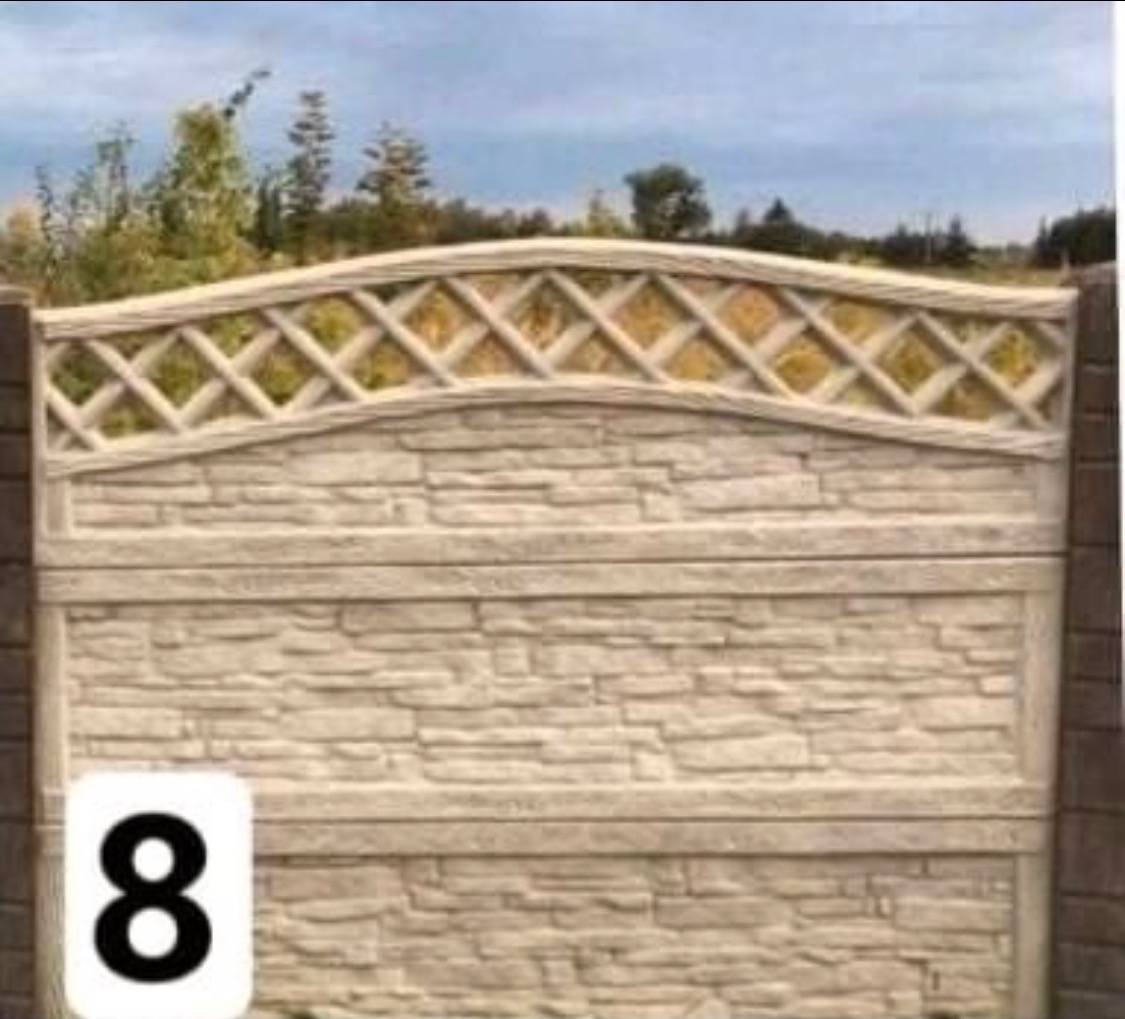 Fragment ogrodzenia z prefabrykatów betonowych o fakturze kamienia, z dekoracyjnym ażurowym panelem górnym, na tle zieleni.