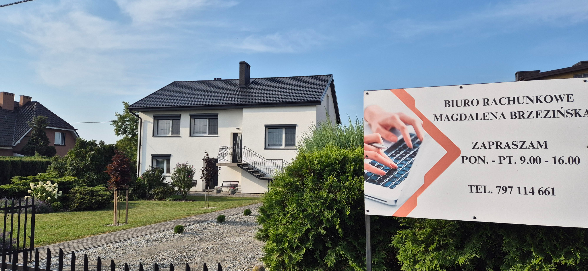 Biuro rachunkowe Magdalena Brzezińska na tle białego budynku z czarnym dachem, z tablicą informacyjną z godzinami otwarcia i numerem telefonu.