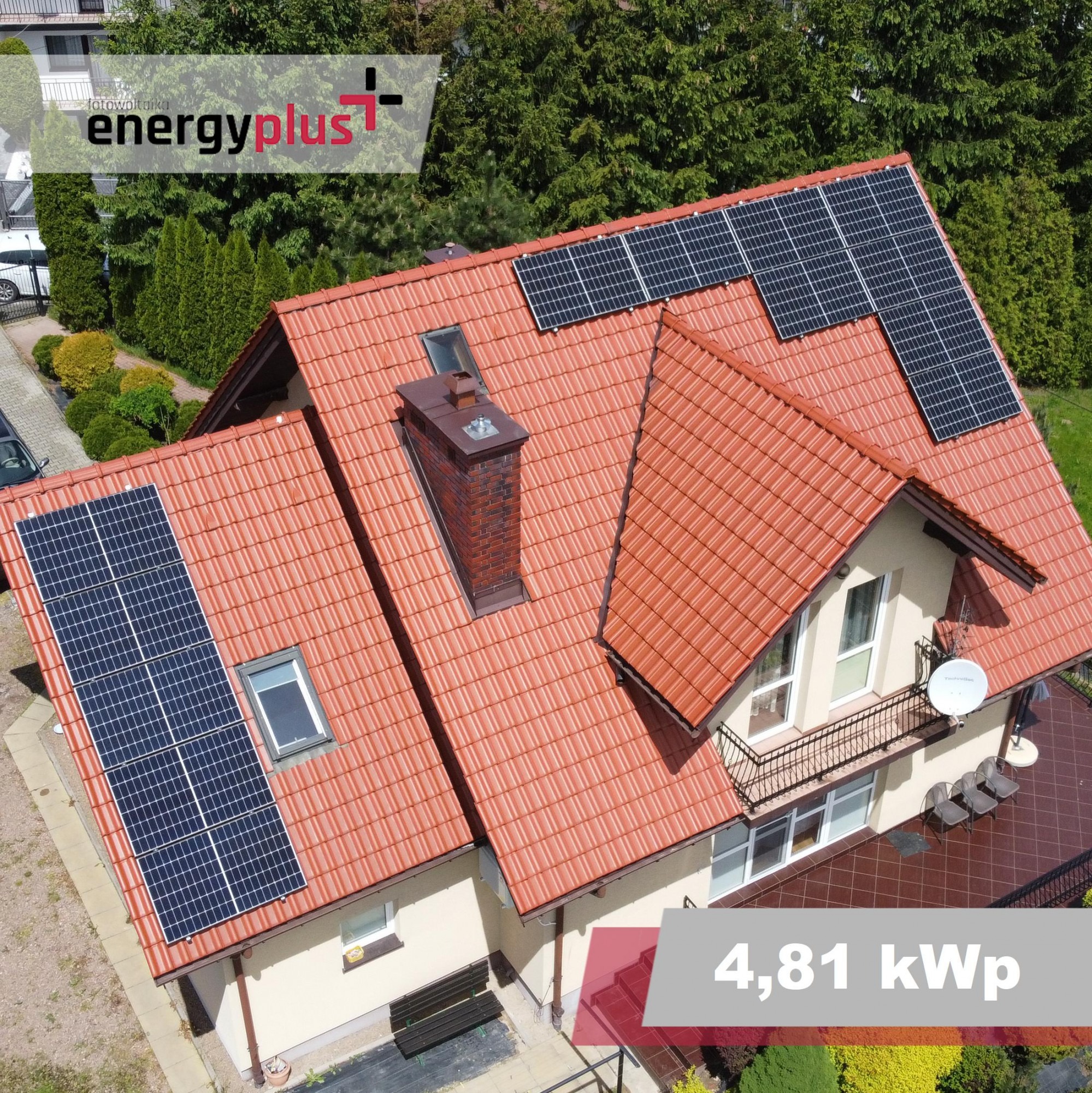 Widok z drona na dom z pomarańczową dachówką i panelami słonecznymi, logo firmy Energy Plus w rogu.