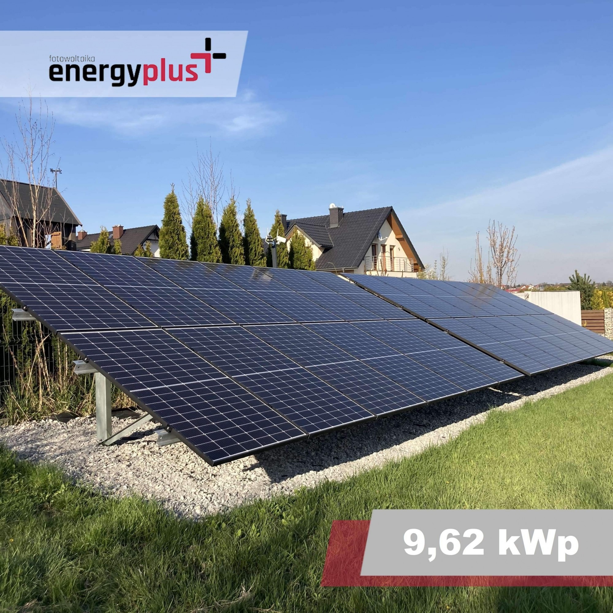 Instalacja paneli słonecznych o mocy 9,62 kWp na trawniku przed domem jednorodzinnym, widoczne panele i konstrukcja wsporcza, w tle domy i drzewa.