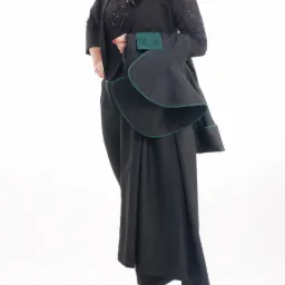 Portret kobiety w czarnym stroju prawniczym z zielonymi lamówkami, pozującej na białym tle.