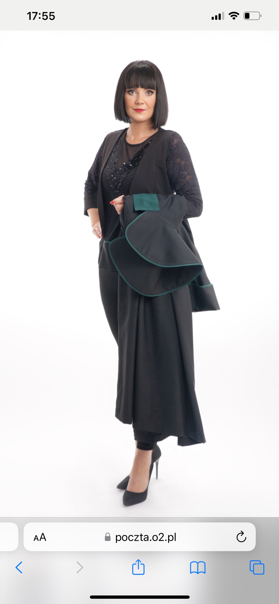 Portret kobiety w czarnym stroju prawniczym z zielonymi lamówkami, pozującej na białym tle.