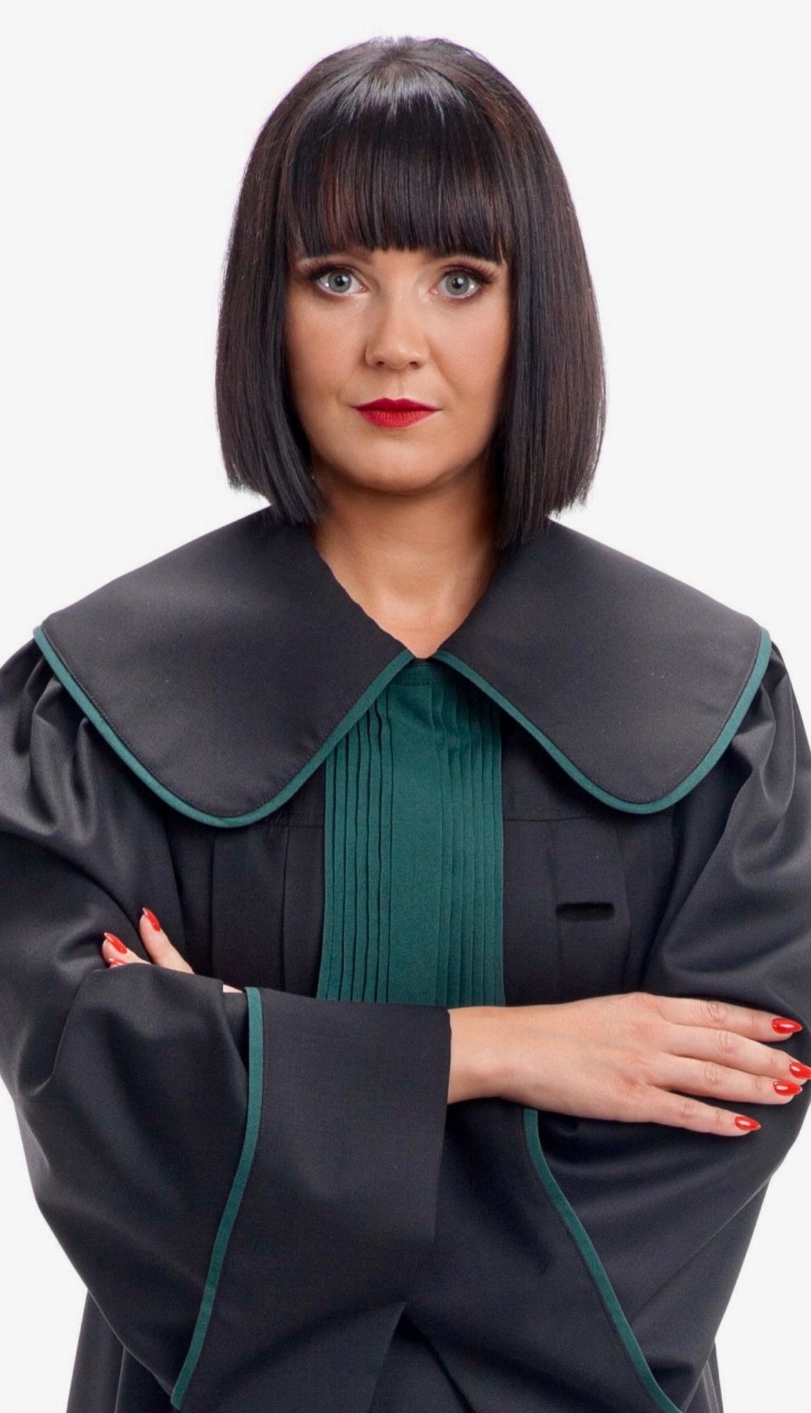 Portret kobiety w todze adwokackiej z zielonymi akcentami, skrzyżowane ręce, czerwone usta i paznokcie, na białym tle.