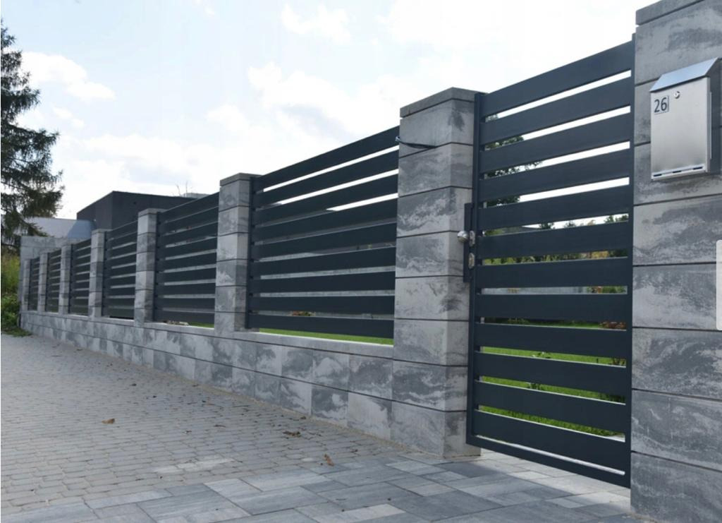 Nowoczesne ogrodzenie z poziomych paneli i szarej betonowej podmurówki z bramą wjazdową oraz skrzynką na listy z numerem 26, widoczne z zewnątrz posesji.