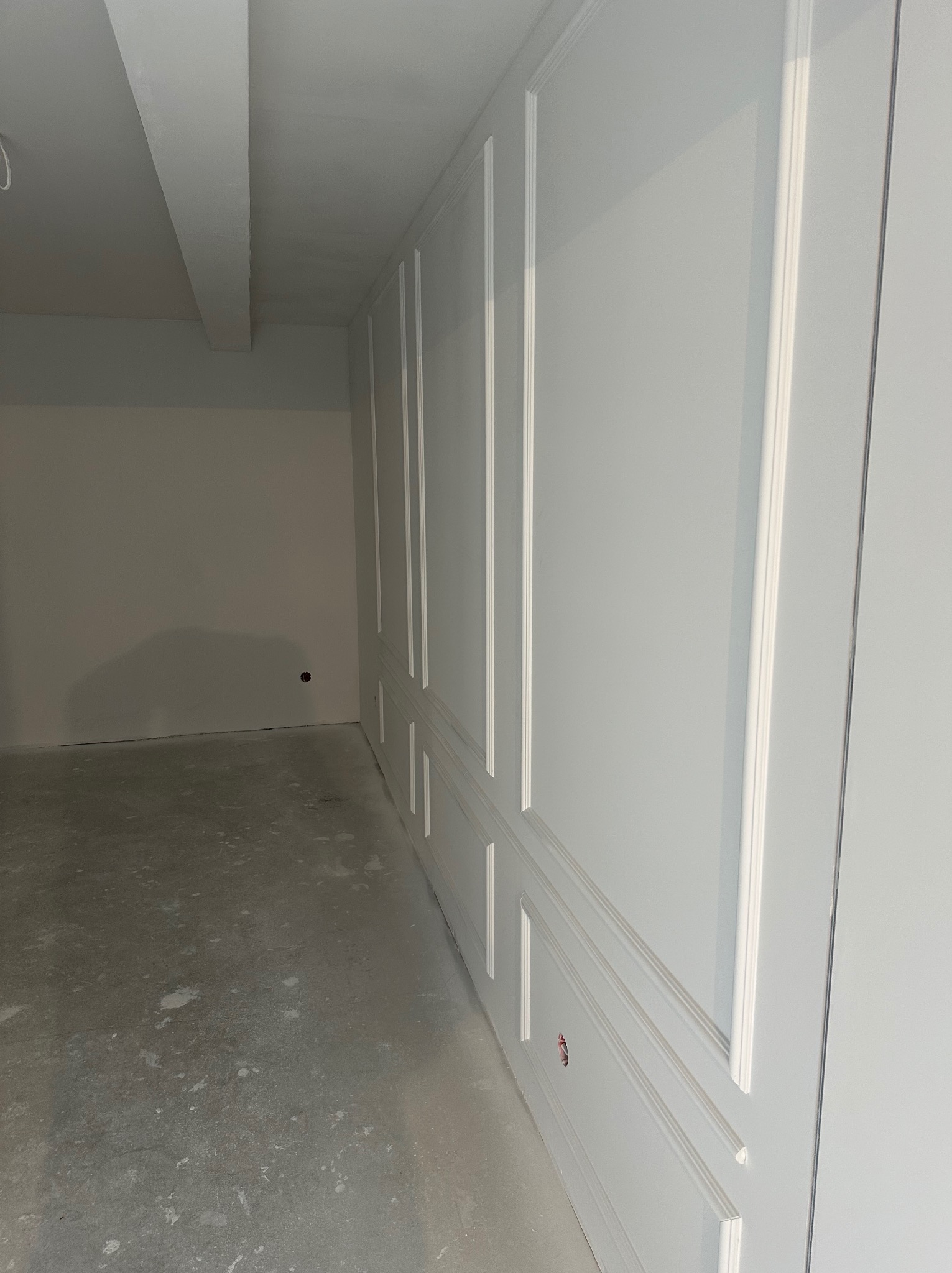 Wykończona ściana z ozdobnymi panelami w Goleniowie. Widoczna surowa podłoga i gładkie ściany. Nowoczesne wykończenie wnętrza.