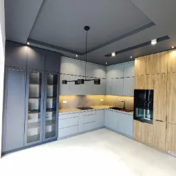 Nowoczesna kuchnia z szarymi szafkami i drewnopodobnym wykończeniem, oświetlenie podszafkowe, czarna armatura i lampa sufitowa.