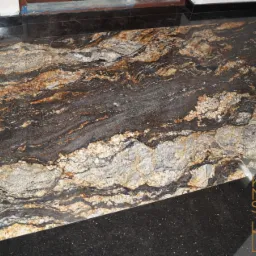 Wykończona podłoga z kamienia naturalnego o bogatym wzorze, w odcieniach brązu, szarości i bieli, otoczona czarną, błyszczącą obwódką. W prawym dolnym rogu widoczne logo firmy.