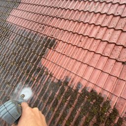 ABC Mycie Wrocław - Czyszczenie czerwonej dachówki ceramicznej z mchu i zabrudzeń za pomocą myjki ciśnieniowej. Widoczna różnica między umytą a zabrudzoną powierzchnią.