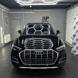 DarkPoint DANIEL KNYS - Błyszczący, czarny samochód Audi z widocznym logo firmy detailingowej Dark Point, zaparkowany w dobrze oświetlonym garażu z podłogą z tworzywa sztucznego.