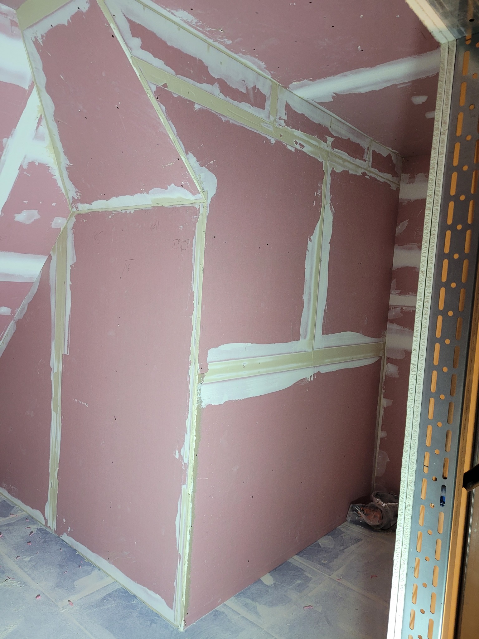 Montaż płyt gipsowo-kartonowych na ścianach i suficie poddasza, widoczne profile metalowe i szpachlowane łączenia. Prace wykończeniowe w trakcie realizacji.