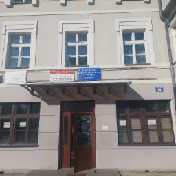 Fasada dwupiętrowego budynku z trzema szyldami kancelarii prawnych nad wejściem, okna z ogłoszeniami o wynajmie powierzchni.