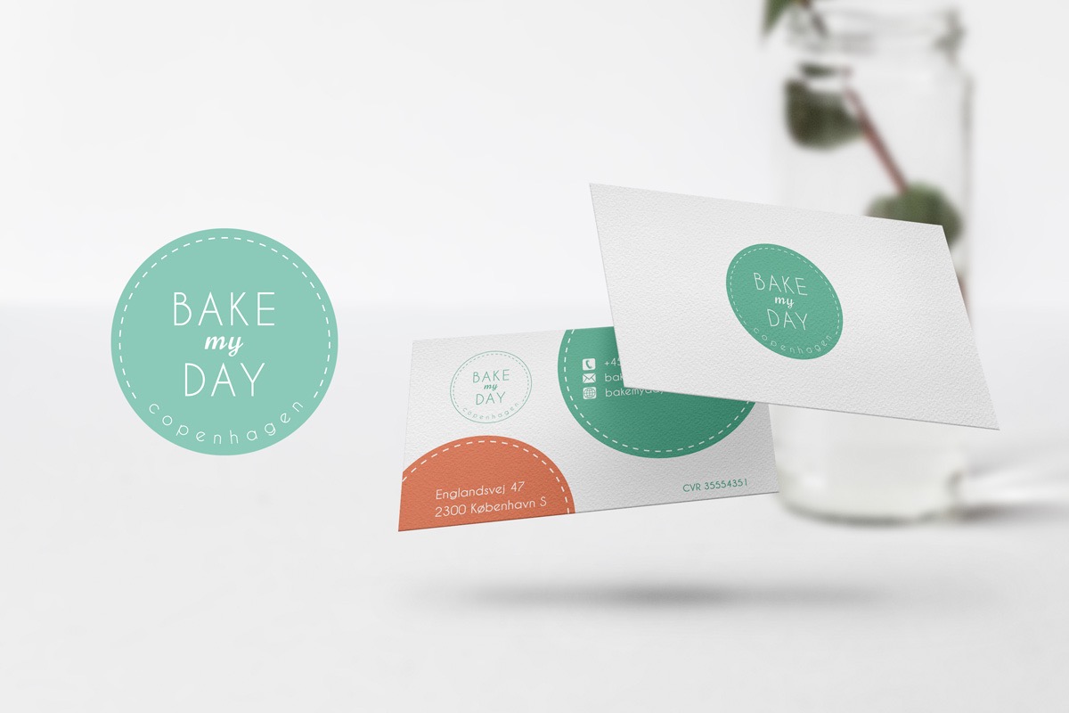 Dwie wizytówki z logo 'Bake my Day Copenhagen' w odcieniach turkusu i pomarańczy, obok okrągłe logo marki na białym tle, w tle rozmyty słoik.