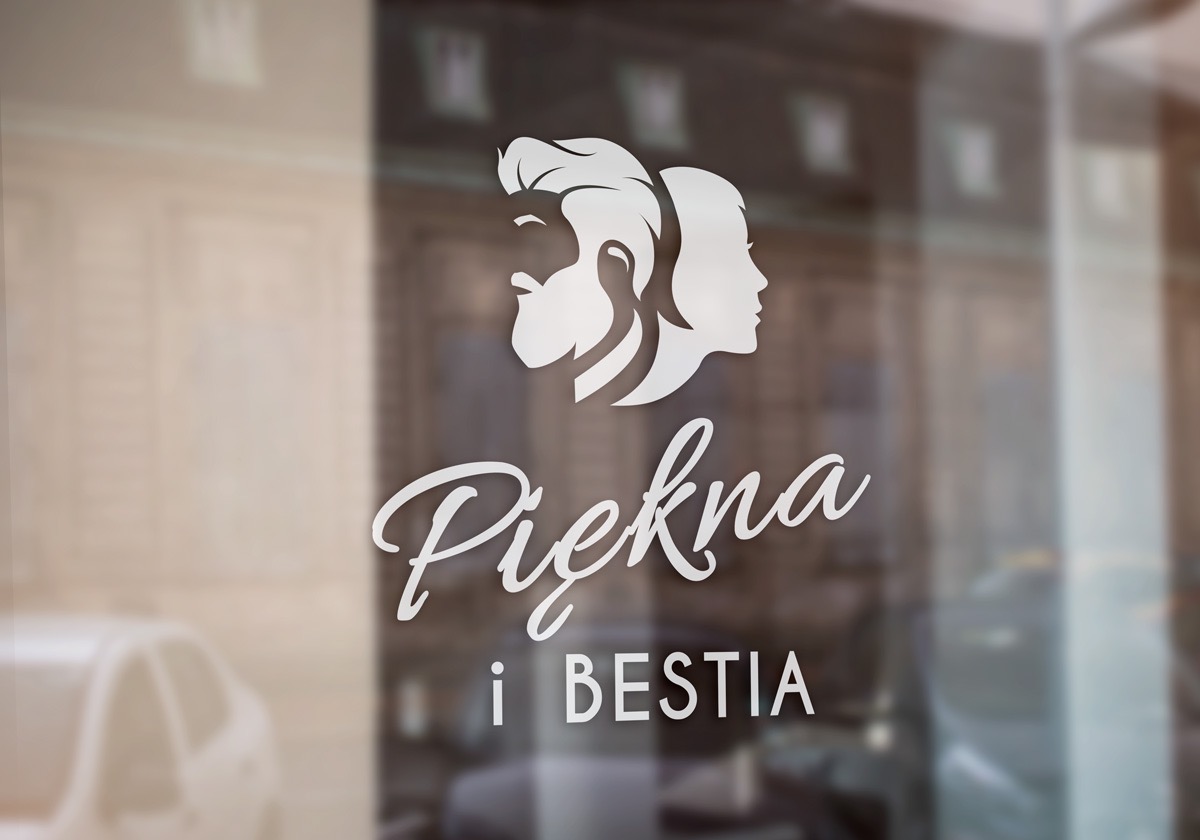 Biały napis 'Piękna i Bestia' oraz grafika przedstawiająca profile kobiety i mężczyzny umieszczone na szklanej witrynie salonu.