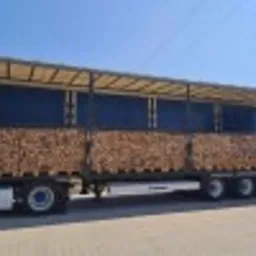 Ciężarówka z niebieską plandeką wypełniona po brzegi pociętymi i ułożonymi kawałkami drewna opałowego, prawdopodobnie dostarczanego do klienta w Sieradzu.