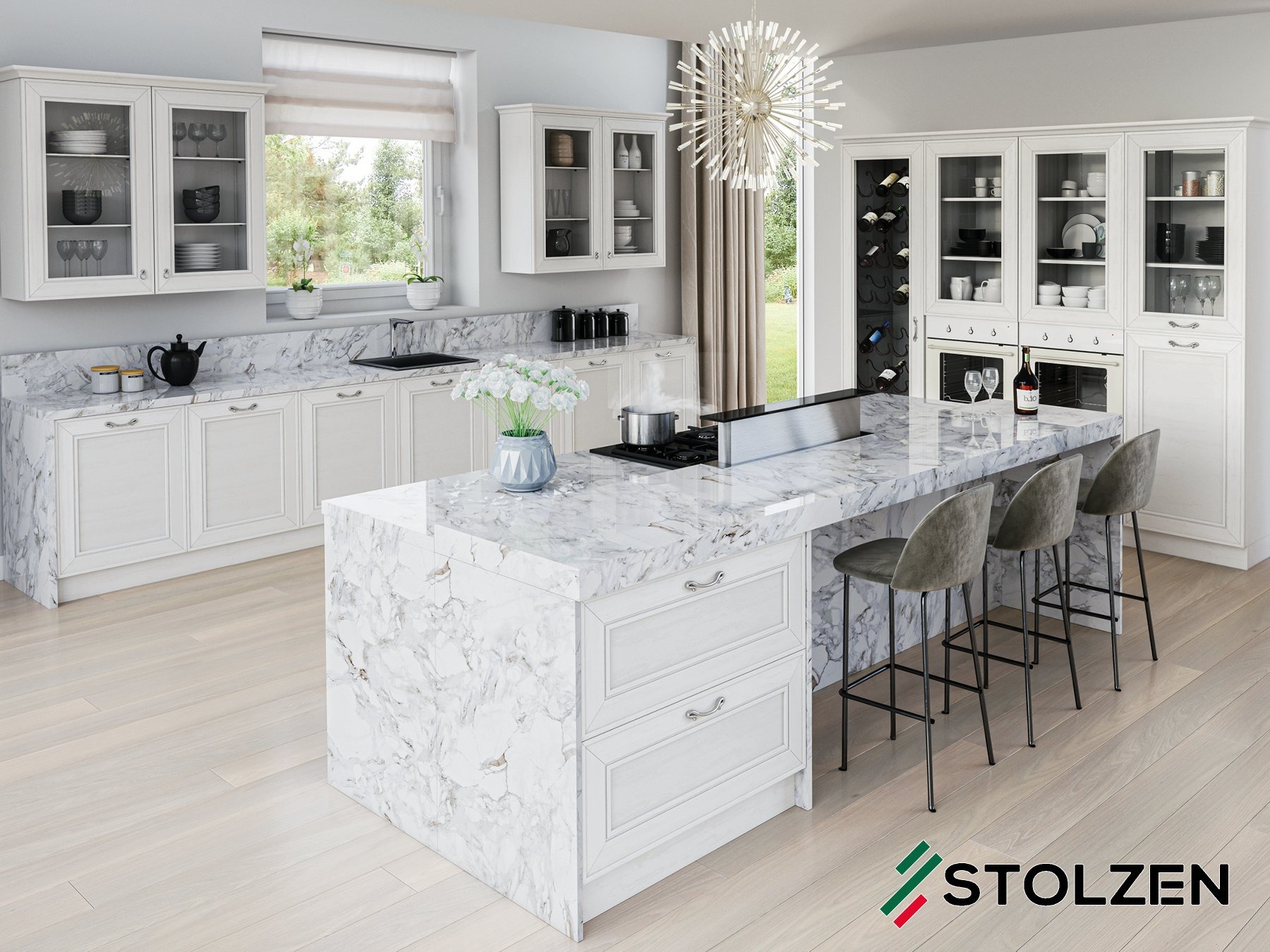 Jasna kuchnia z marmurowym blatem, wyspą kuchenną i szklanymi witrynami, oświetlona nowoczesnym żyrandolem. Na blacie kwiaty w wazonie oraz garnki na płycie grzewczej.